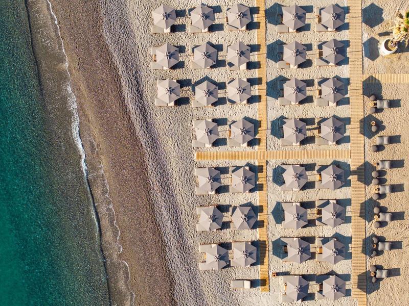 Aerial view of a beach section with rows of umbrellas and chairs next to the sea