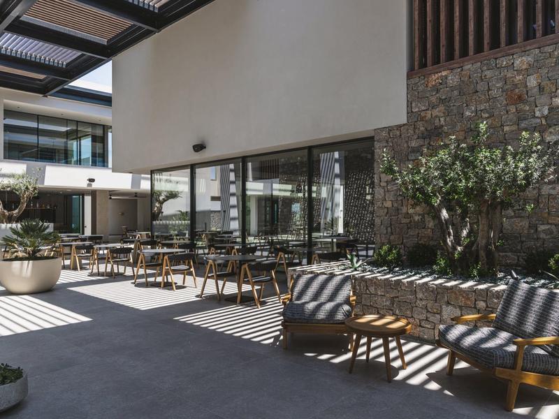 Modern hotel restaurant with outdoor seating and cozy shaded lounge area.