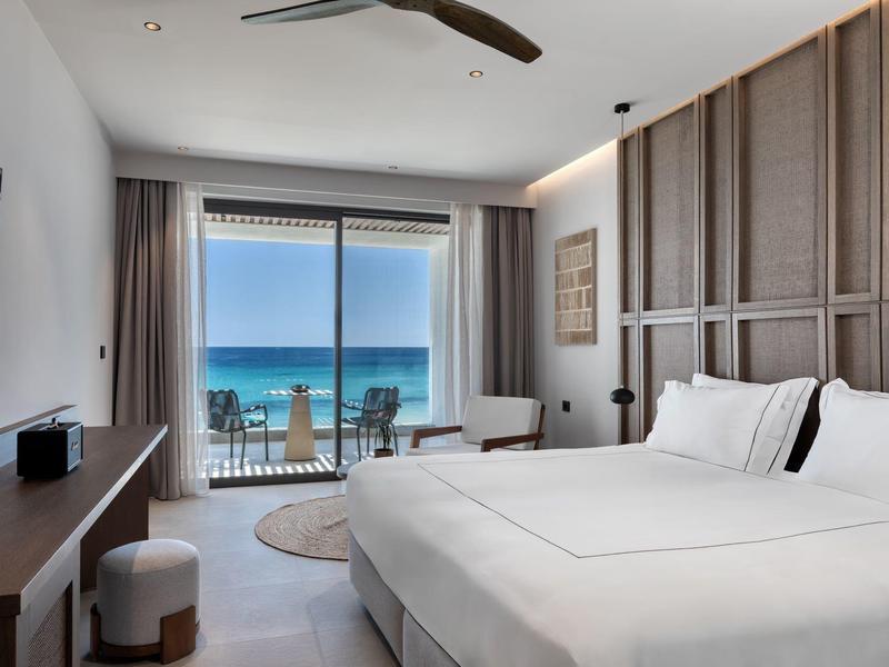 Modern hotel room with sea view, double bed, desk, and balcony.