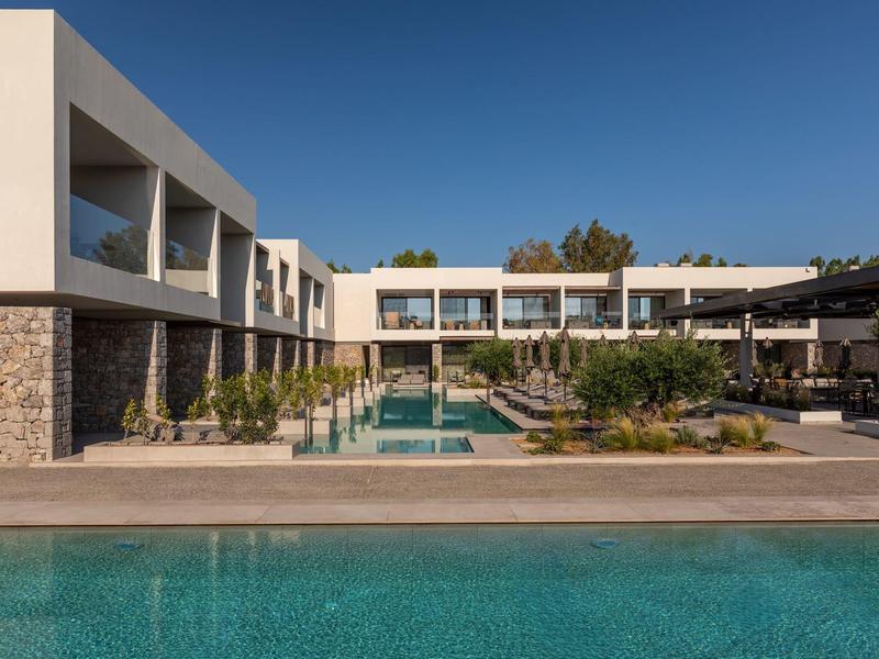 Modern hotel with outdoor pool, clean lines, and sunny sky.