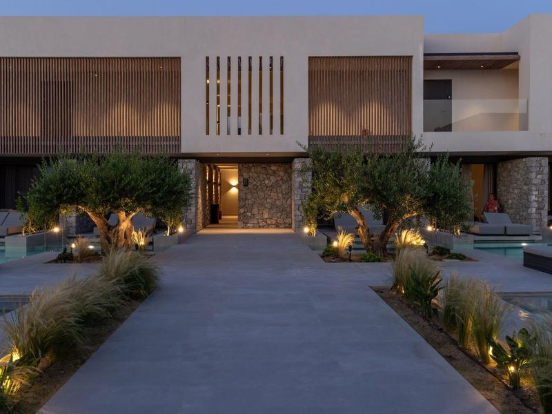 Modern hotel entrance with lighting and plants in the evening.