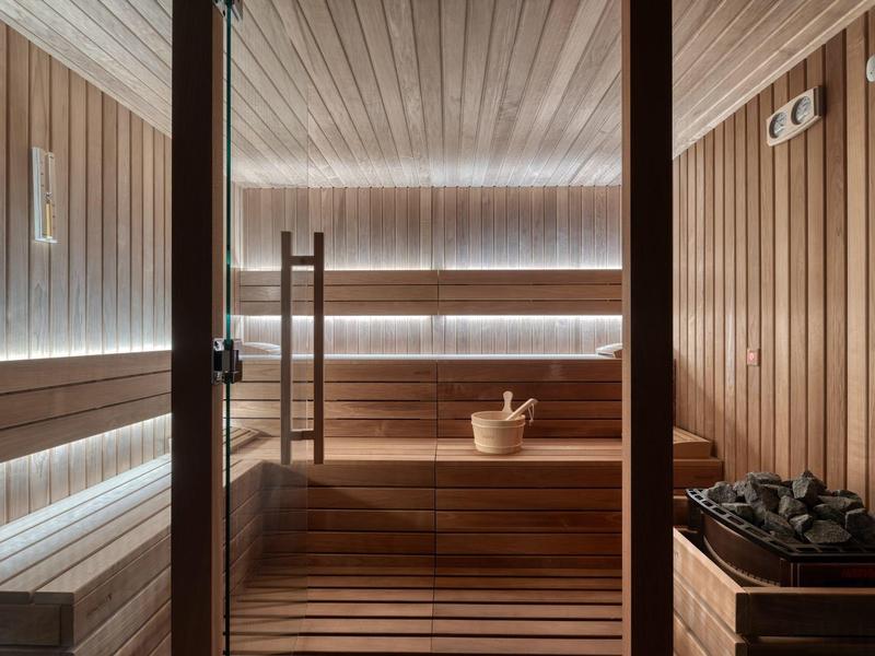 Sauna with wooden benches, bucket, and ladle, calm atmosphere for relaxation in a hotel.