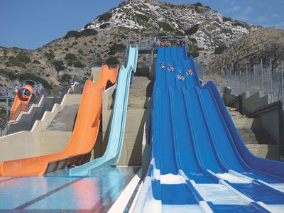 Mehrere bunte Wasserrutschen an einem Berg mit blauer Himmel im Hintergrund.