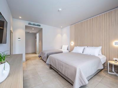 Nowoczesny pokój hotelowy z dwoma łóżkami, jasną drewnianą ścianą i stylowym oświetleniem