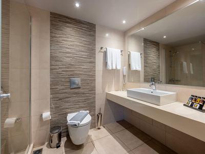 Nowoczesna łazienka z umywalką, toaletą i dużą ścianą z lustrem.