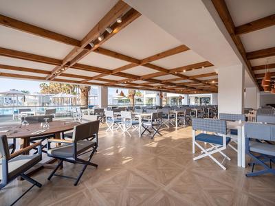 Helle Lounge mit Holzbalkendecke, dunklen Stühlen und großen Fenstern mit Hafenblick.