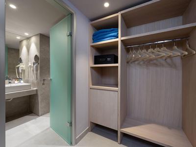 Jasna garderoba z otwartymi półkami i widokiem na nowoczesną łazienkę.