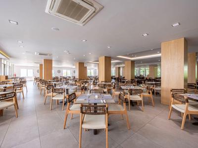 Duża, jasna jadalnia z drewnianymi stołami i krzesłami w hotelu.