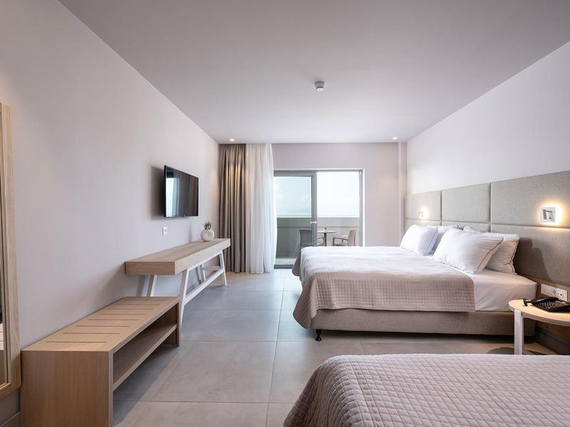 Nowoczesny pokój hotelowy z łóżkiem podwójnym i balkonem z widokiem na morze.