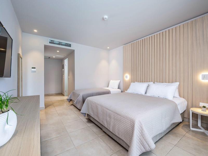 Nowoczesny pokój hotelowy z dwoma łóżkami, jasną drewnianą ścianą i stylowym oświetleniem