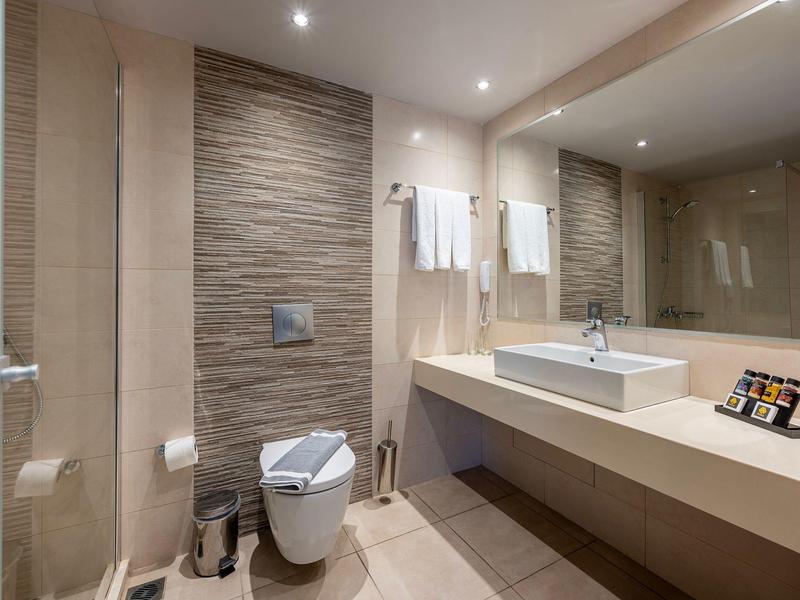 Nowoczesna łazienka z umywalką, toaletą i dużą ścianą z lustrem.