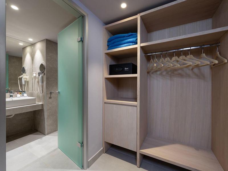 Jasna garderoba z otwartymi półkami i widokiem na nowoczesną łazienkę.