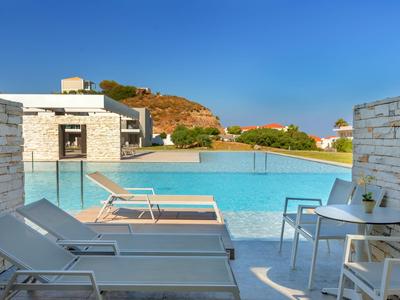 Nowoczesny basen z leżakami, miejscem do siedzenia i widokiem na wzgórze pod czystym niebem.