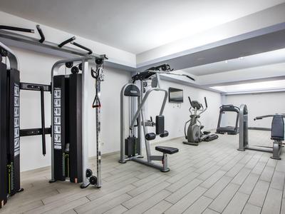 Moderner Fitnessraum mit Kraftgeräten und Cardio-Geräten in einem hellen Raum.