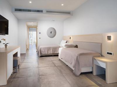 Nowoczesny pokój hotelowy z dwoma pojedynczymi łóżkami, telewizorem płaskoekranowym i biurkiem.