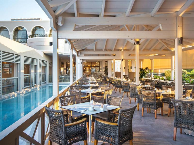 Nowoczesna restauracja hotelowa zewnętrzna obok basenu w świetle dziennym.