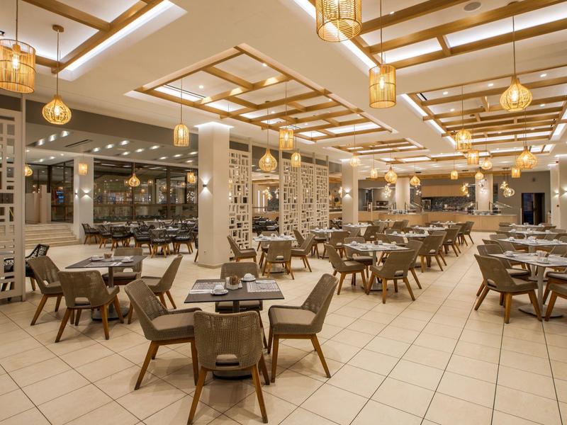 Duża nowoczesna jadalnia z wieloma stolikami i ciepłym oświetleniem.