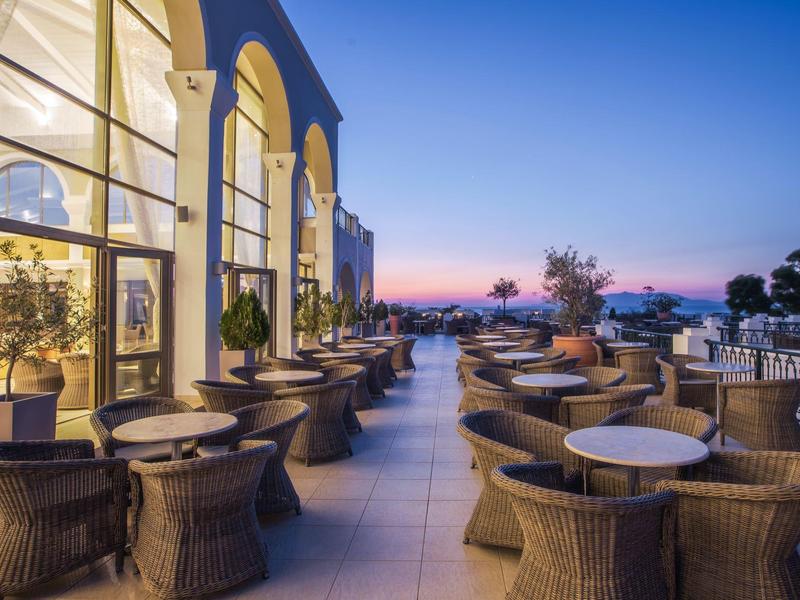 Taras z różnymi krzesłami i stołami obok budynku o zachodzie słońca.