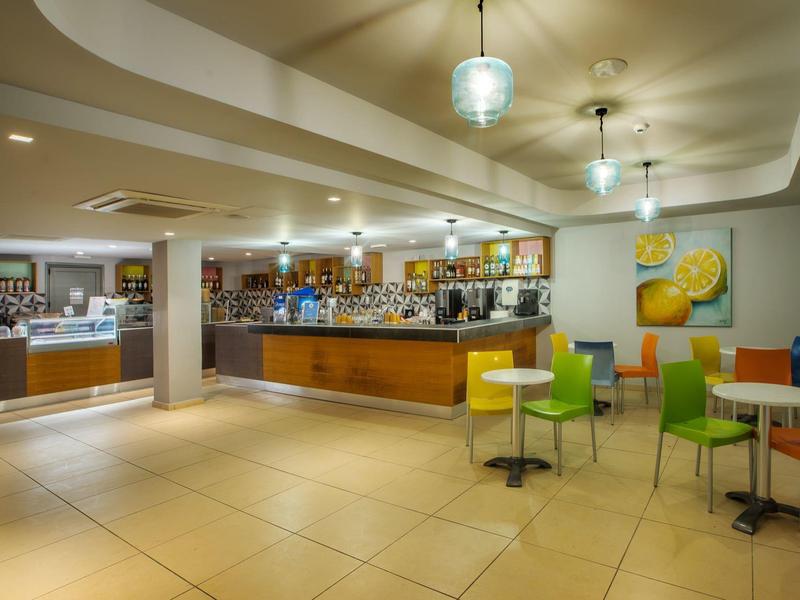 Nowoczesny bar hotelowy z kolorowymi krzesłami, stołami i jasnym oświetleniem.