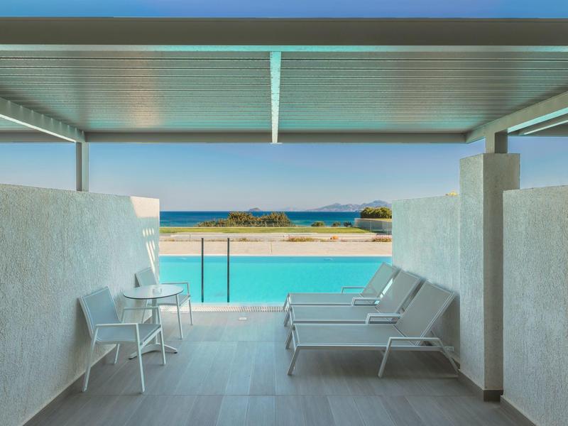 Zadaszony taras z leżakami z widokiem na basen i morze