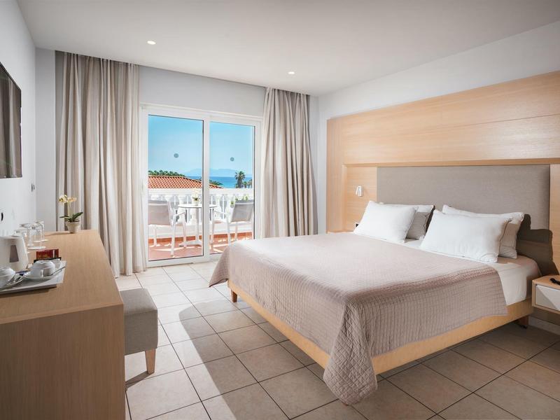 Nowoczesny pokój hotelowy z łóżkiem podwójnym, balkonem i widokiem na miasto.