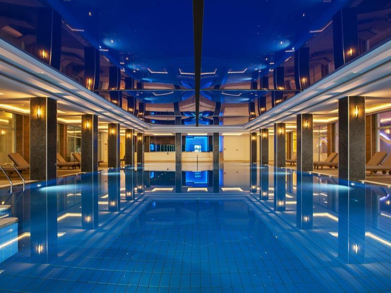 Hotelowy basen kryty nocą z odbiciem i nowoczesnym oświetleniem