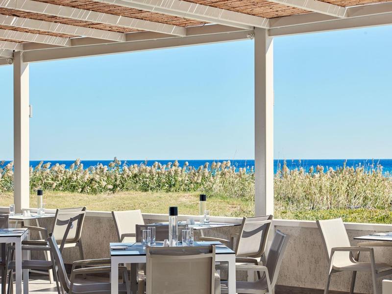 Otwarty taras hotelowy z miejscami do siedzenia i widokiem na morze przy czystym niebie.