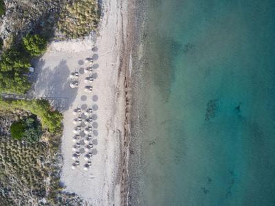 Luchtfoto van een strand met parasols en helder blauwgroen water.