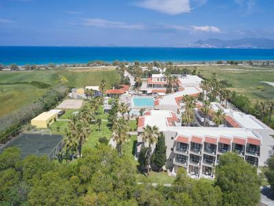 Uitzicht op een hotelresort met zwembad en zee op de achtergrond onder een blauwe lucht.