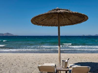 Strand met ligstoelen, tafel en parasol bij zee onder heldere lucht