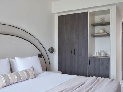 Modern ingerichte hotelkamer met comfortabel bed en kast in neutrale kleuren.
