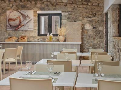 Lichte, gezellige eetruimte met natuurstenen muren en witte tafels in een hotel.