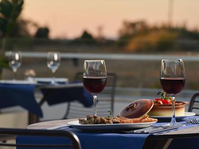 Buitentafel met twee glazen rode wijn en borden met eten bij zonsondergang