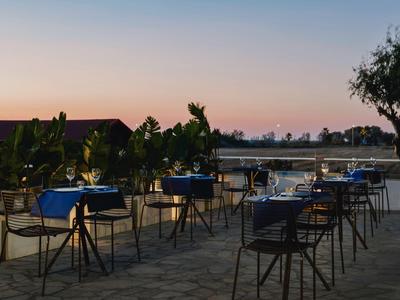 Leeg buitenterras van een restaurant met tafels en stoelen bij zonsondergang.
