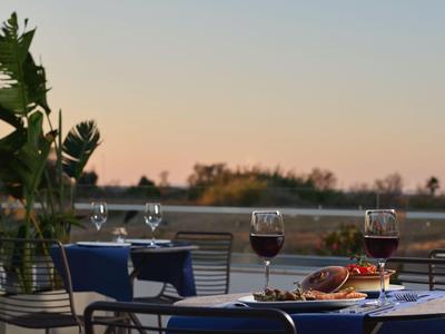 Tisch auf der Terrasse mit Wein, Brötchen und Blick auf den See bei Sonnenuntergang.