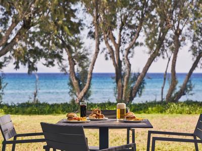 Ein Tisch mit Speisen und Getränken im Freien mit Blick auf Meer und Bäume
