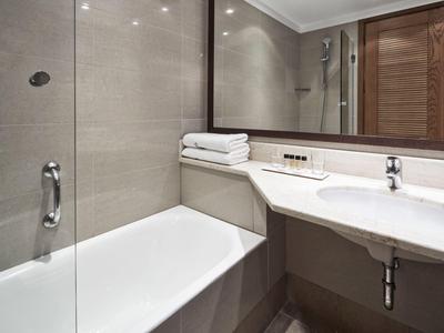Modernes Badezimmer mit Badewanne, Waschtisch und großen Spiegeln in neutralen Farben.