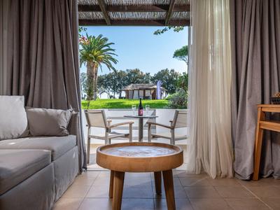 Gemütliche Lounge mit Blick auf einen grünen, palmengesäumten Garten und Terrasse.