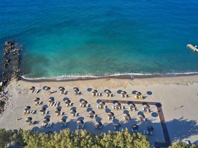 Strand mit blauem Wasser, Sonnenschirmen und Palmen, ideal für Urlaub.