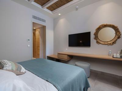Modernes Hotelzimmer mit Bett, Wand-TV, Holzspiegel und Schreibtischbereich.
