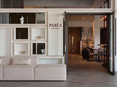 Moderner Hotel-Loungebereich mit bequemer Sofa und offenem Durchgang zu Restaurant.