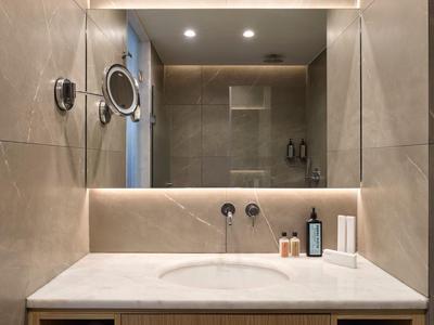 Moderner Badezimmerspiegel mit Vergrößerungsglas und Waschbecken im Hotelzimmer.