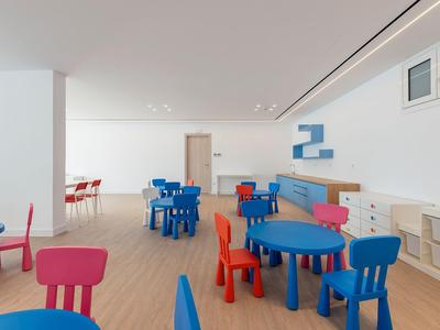 Ein heller, moderner Speisesaal mit bunten blauen, roten und pinken Stühlen und Tischen.