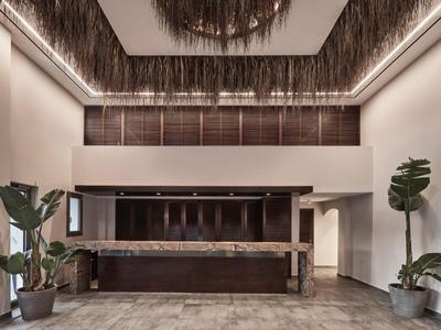Moderner Hotel-Empfangsbereich mit hohen Decken, Pflanzen und elegantem Design.