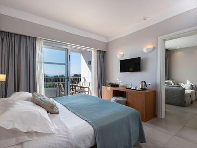 Modernes Hotelzimmer mit Doppelbett, TV, Balkon und angrenzendem Badezimmer.