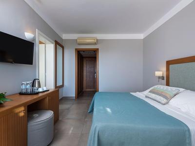 Modernes Hotelzimmer mit blauem Bett, TV und Schreibtisch.