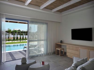 Modern eingerichtetes Hotelzimmer mit Blick auf einen Pool und Garten durch eine große Fensterfront.