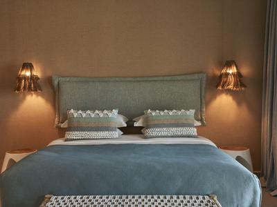 Modernes Schlafzimmer mit Doppelbett, gepolstertem Kopfteil und warmem Wandlicht.