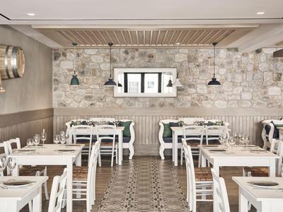Helles Restaurant mit weißen Holztischen und Steinwand im Hotel.