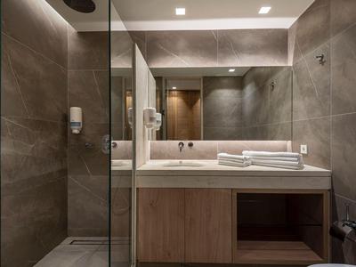 Modernes Badezimmer mit Glasdusche, großem Spiegel und hölzernem Waschtischunterschrank.